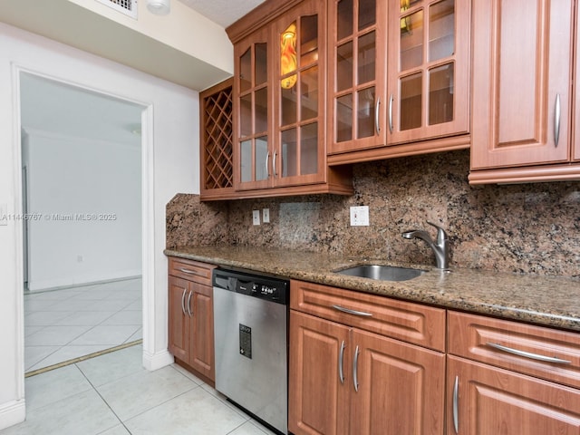 kitchen featuring backsplash, stone counters, light tile patterned floors, and stainless steel dishwasher