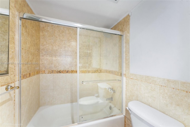 bathroom with bath / shower combo with glass door, tile walls, and toilet