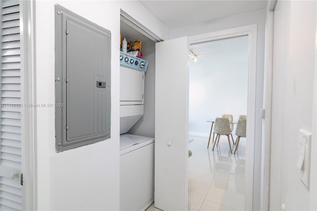 washroom with light tile floors and stacked washing maching and dryer