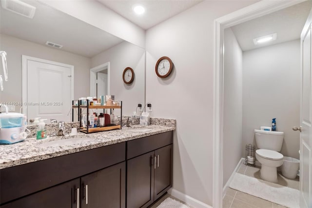 bathroom with toilet, dual bowl vanity, and tile floors