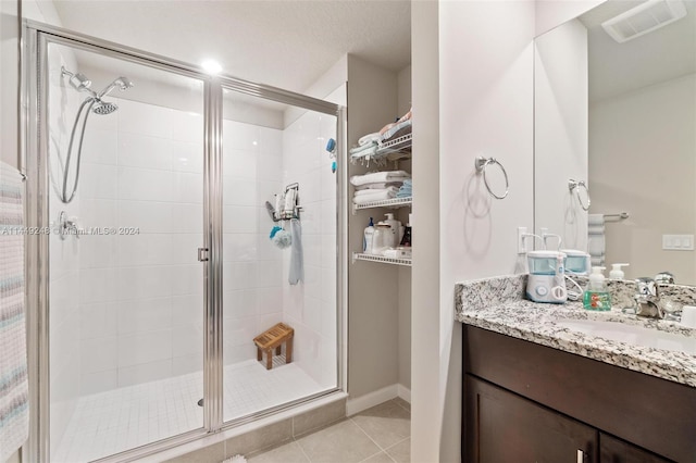 bathroom with vanity with extensive cabinet space, tile flooring, and a shower with shower door