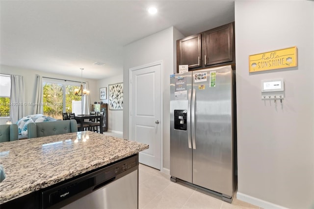 kitchen featuring light tile floors, light stone counters, stainless steel appliances, an inviting chandelier, and decorative light fixtures