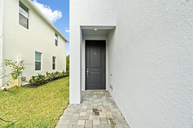 view of exterior entry featuring a lawn