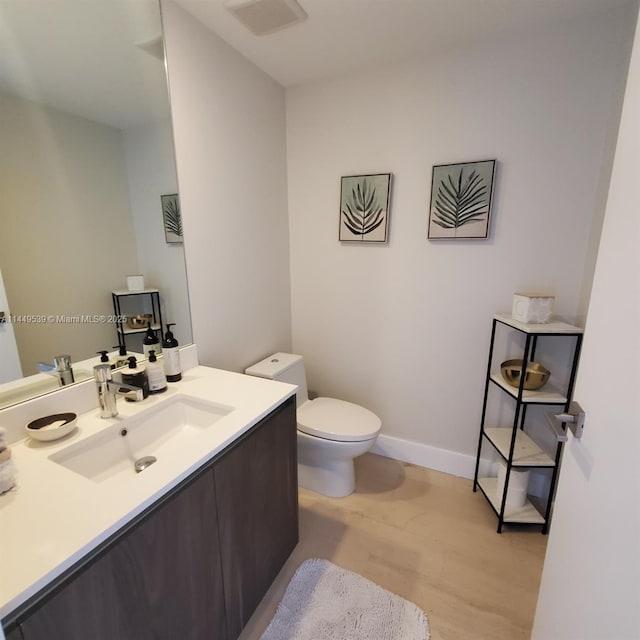 bathroom with wood-type flooring, toilet, and vanity