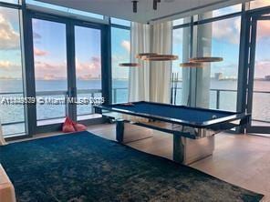 rec room with pool table, a wealth of natural light, and a water view