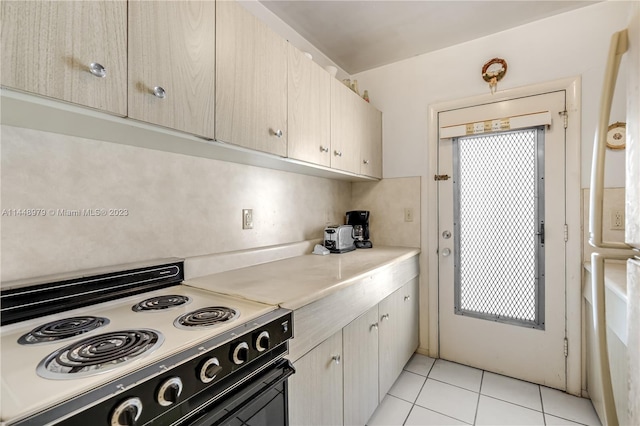 kitchen featuring light brown cabinetry, light tile floors, and range