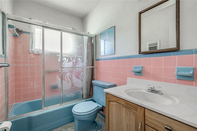 full bathroom with tile walls, backsplash, toilet, enclosed tub / shower combo, and vanity