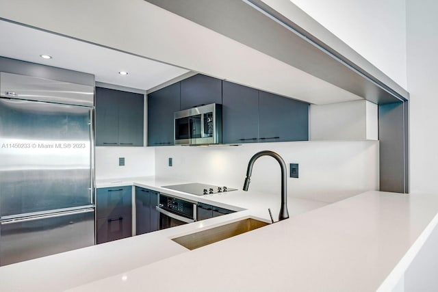 kitchen featuring stainless steel appliances, blue cabinetry, tasteful backsplash, and sink