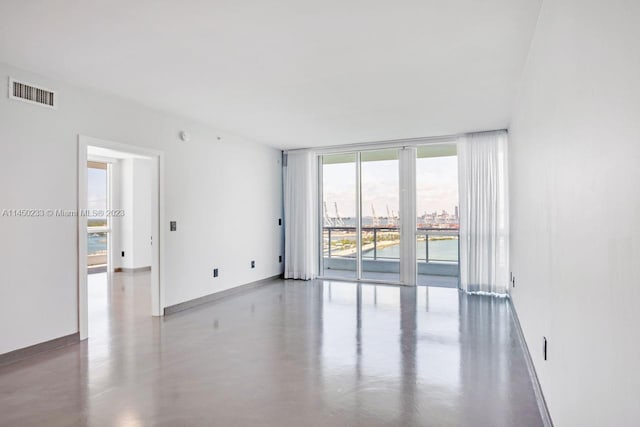 spare room featuring concrete flooring and floor to ceiling windows