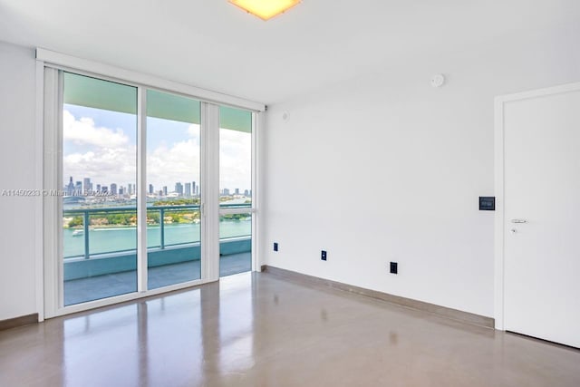 spare room with floor to ceiling windows, a wealth of natural light, and concrete flooring