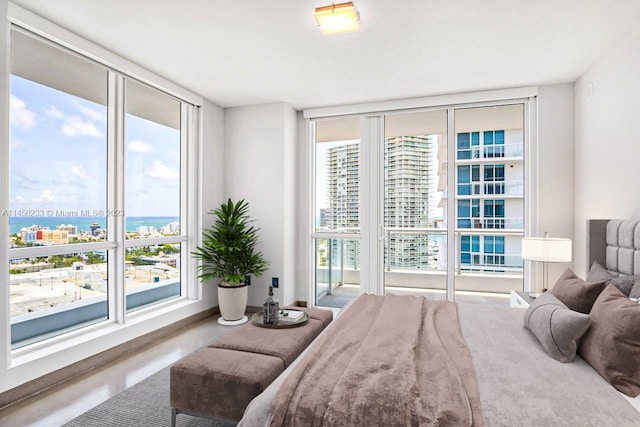 bedroom featuring floor to ceiling windows, a water view, and access to outside