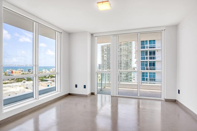 unfurnished room featuring concrete flooring, a water view, and expansive windows