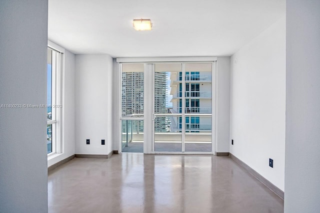 spare room with a wall of windows and concrete flooring