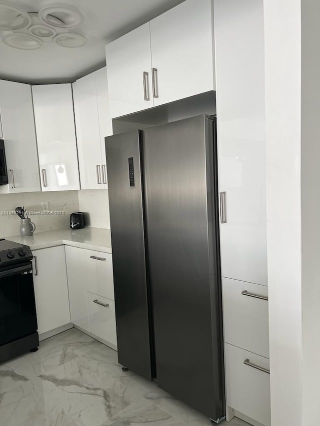 kitchen with white cabinets, appliances with stainless steel finishes, tasteful backsplash, and light tile floors