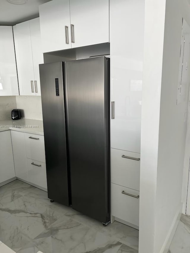 interior space featuring stainless steel fridge, light tile flooring, and tasteful backsplash