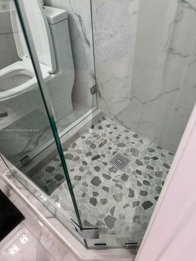 room details with a tile shower, tile floors, and toilet