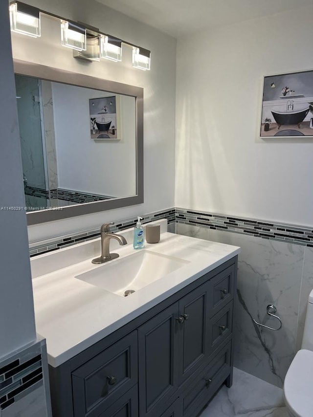 bathroom with tile walls, toilet, vanity, and tile flooring