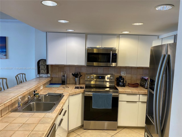 kitchen with tile countertops, stainless steel appliances, and white cabinets