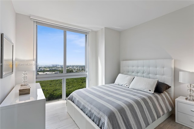 bedroom featuring a wall of windows and light hardwood / wood-style flooring