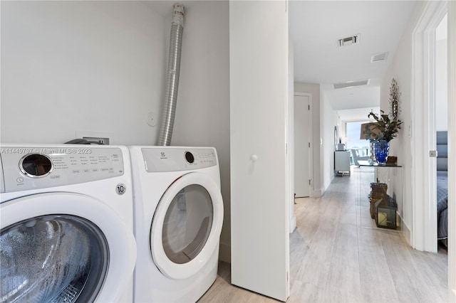 laundry area with washer hookup, washing machine and dryer, and light hardwood / wood-style floors