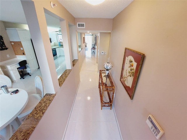 hallway with light tile flooring and a textured ceiling