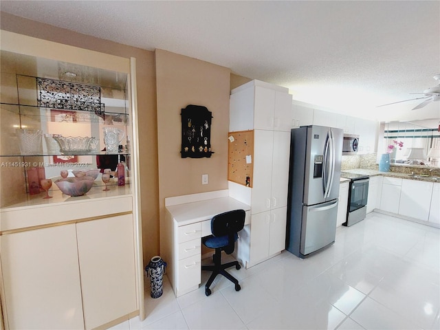 interior space featuring a textured ceiling, ceiling fan, stainless steel appliances, and white cabinets