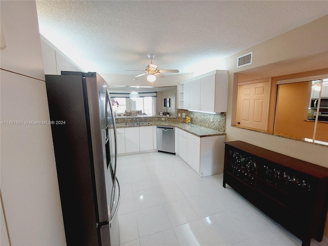 kitchen with light tile flooring, stainless steel appliances, ceiling fan, white cabinets, and a textured ceiling