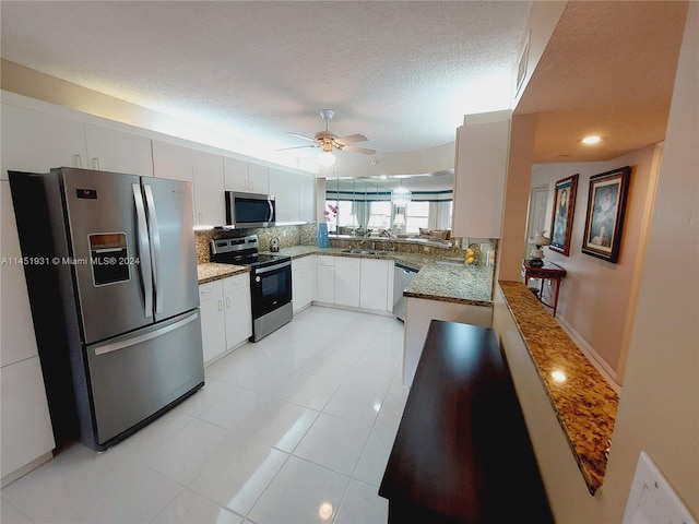 kitchen with a textured ceiling, stainless steel appliances, white cabinets, tasteful backsplash, and ceiling fan