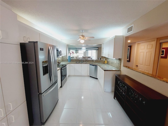 kitchen featuring ceiling fan, a textured ceiling, light tile floors, white cabinetry, and appliances with stainless steel finishes