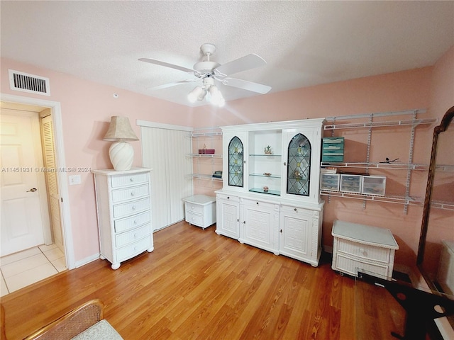 interior space featuring ceiling fan, light hardwood / wood-style flooring, and a textured ceiling