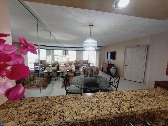 dining area featuring an inviting chandelier, a textured ceiling, and light tile flooring