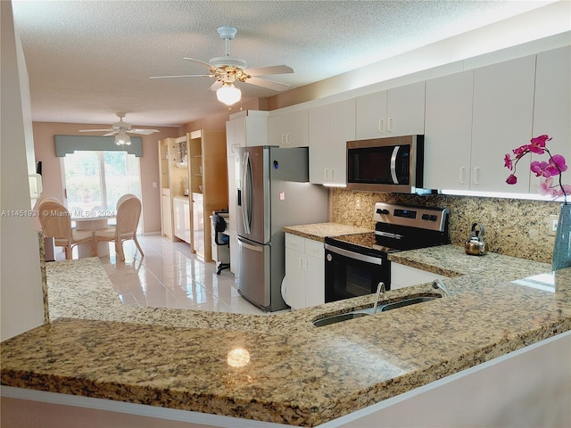 kitchen featuring appliances with stainless steel finishes, sink, a textured ceiling, and light stone countertops