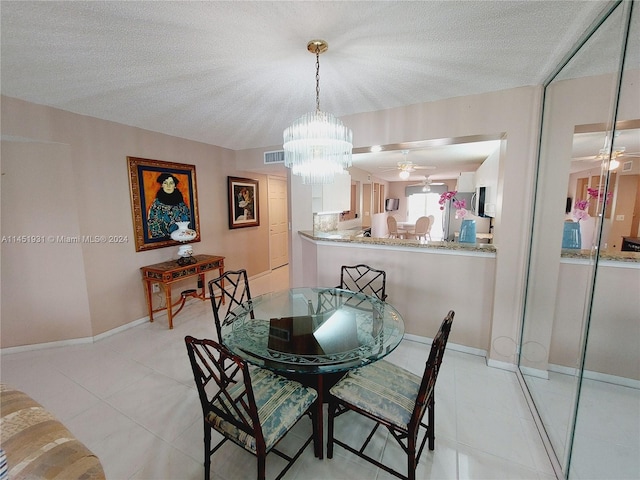 dining room with ceiling fan with notable chandelier, a textured ceiling, and light tile floors