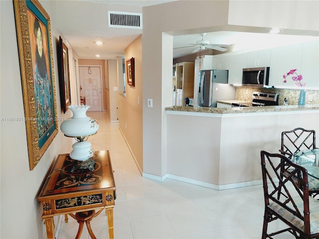 kitchen with ceiling fan, stainless steel appliances, white cabinets, and light tile floors