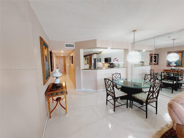 dining area with ceiling fan with notable chandelier, a textured ceiling, and light tile floors