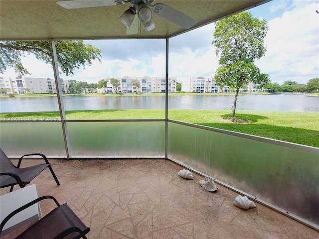 unfurnished sunroom featuring a water view, plenty of natural light, and ceiling fan