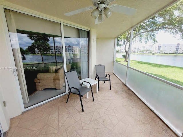 sunroom with a water view and ceiling fan