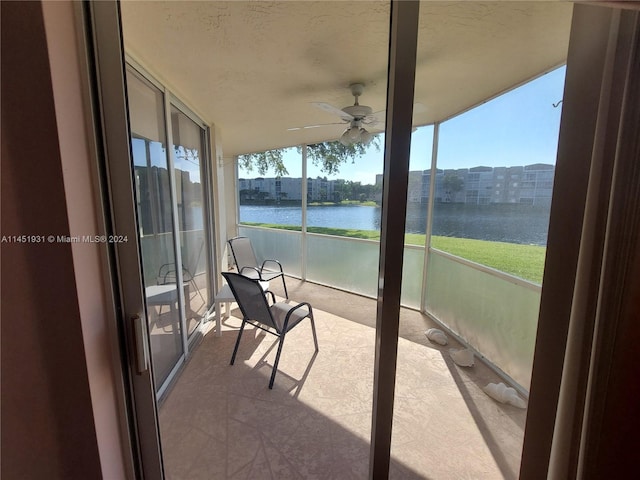 sunroom featuring a water view and ceiling fan