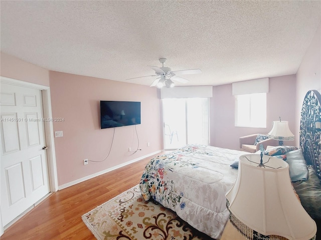 bedroom featuring ceiling fan, light hardwood / wood-style floors, and a textured ceiling