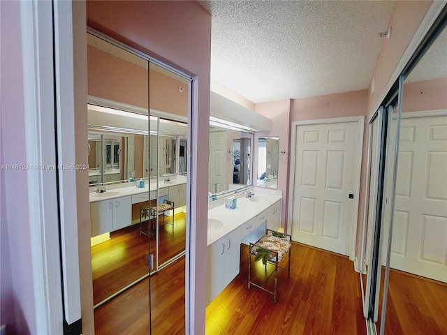 bathroom with wood-type flooring, double vanity, and a textured ceiling