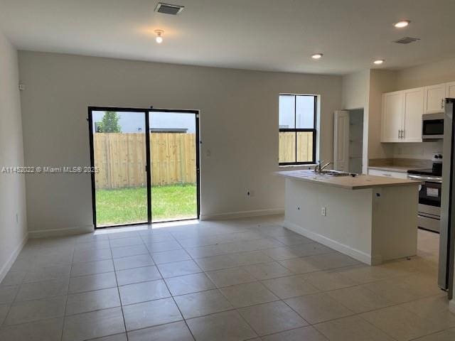 kitchen featuring sink, light tile patterned floors, a kitchen island with sink, stainless steel appliances, and white cabinets