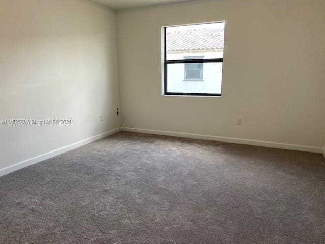 unfurnished room featuring dark carpet