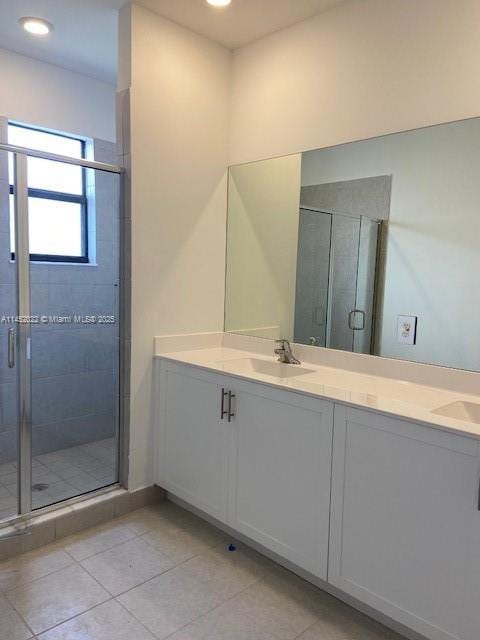 bathroom featuring tile patterned floors, a shower with shower door, and vanity