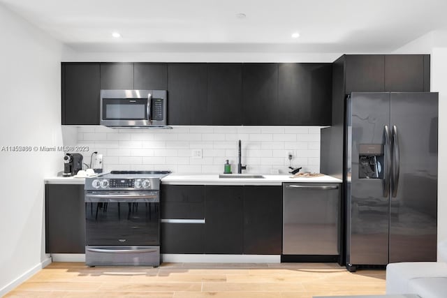 kitchen featuring tasteful backsplash, light hardwood / wood-style floors, appliances with stainless steel finishes, and sink