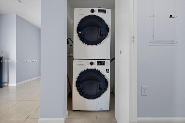 laundry room with stacked washer and clothes dryer, light tile patterned floors, and electric panel