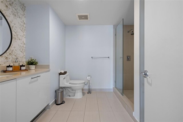 bathroom with toilet, a tile shower, vanity, and tile patterned floors