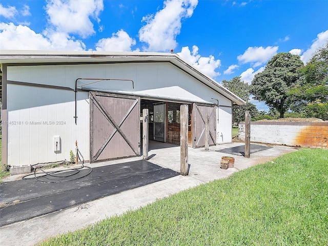 back of property featuring an outdoor structure and a yard