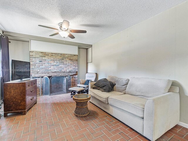 living room featuring brick wall, ceiling fan, a textured ceiling, and a fireplace