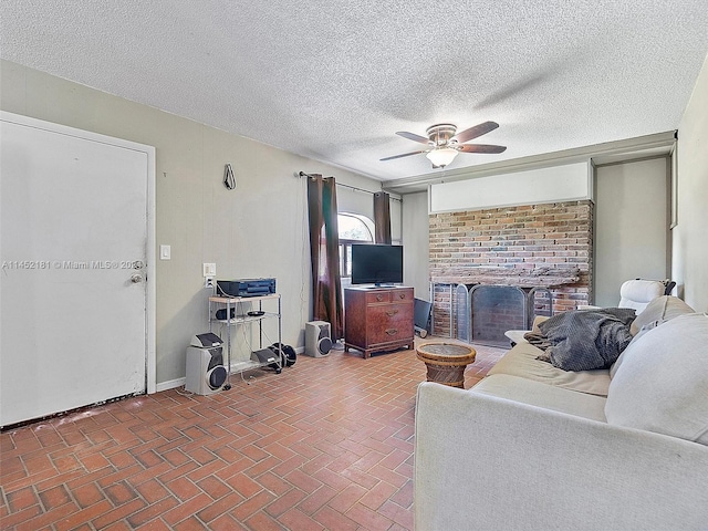 living room with brick wall, a brick fireplace, ceiling fan, and a textured ceiling