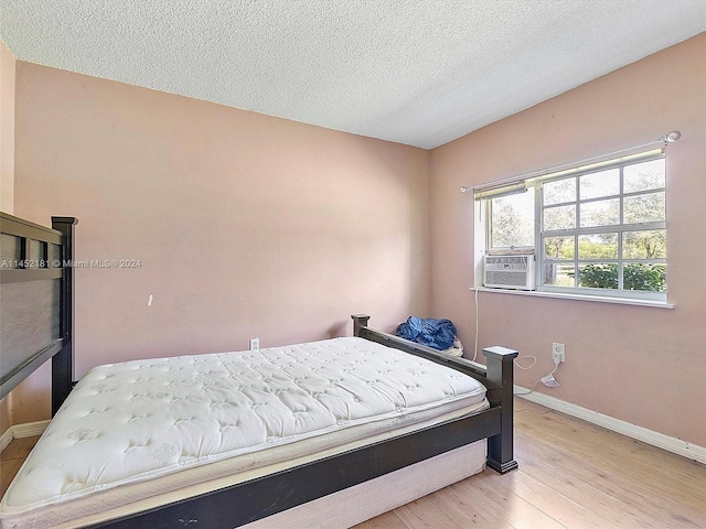 bedroom featuring a textured ceiling and light hardwood / wood-style flooring